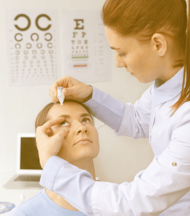 an optometrist administering eyedrop in a woman's eye