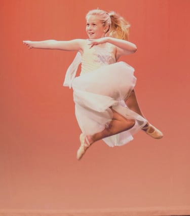 a young girl in a white dress is jumping in the air