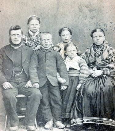 A bearded man, his wife, three daughters and one son in traditional dress circa 1890s