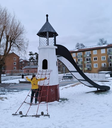 Bild på Jessica framför en fyr på en lekplats. Snö på marken.