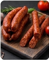 Longanizas y chorizos en una tabla de madera con hierbas frescas y tomates