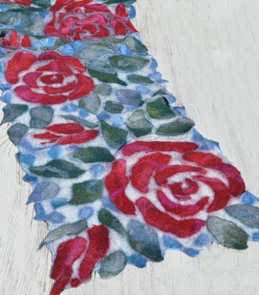 Handmade nuno felted wool scarf with red rose pattern and green leaves on a blue silk background.