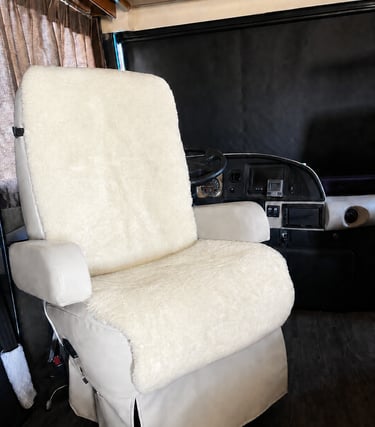Cream sheepskin seat cover installed on a swivel captain chair in a luxury motorhome interior.