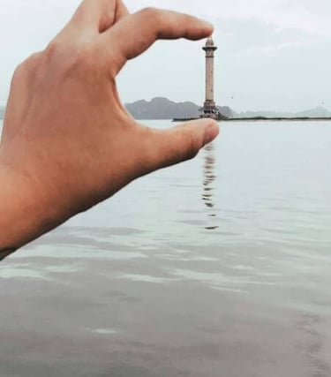 a person holding a small light house in the water
