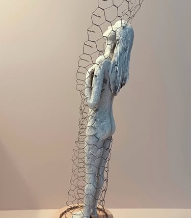 A standing female figure, leaning back and relaxing, surrounded by a wire netting enclosure