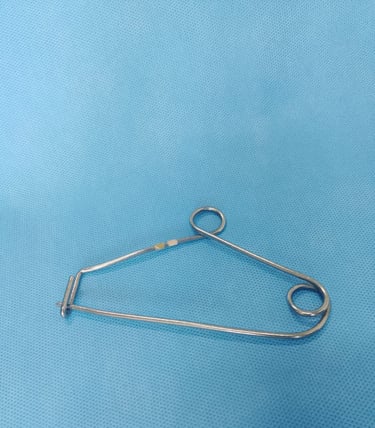 Clipe de Mayo sobre tecido azul estéril, usado para organizar pinças cirúrgicas na mesa de instrumen
