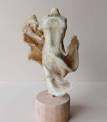 Clay and canvas sculpture of a female torso, wearing windswept, ragged clothes.
