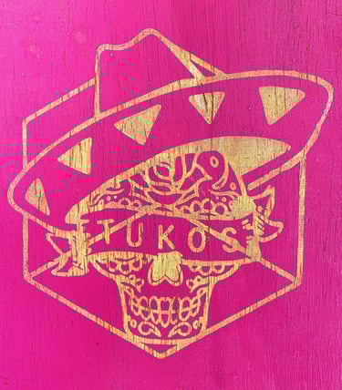 a pink and gold painted wooden sign with a mexican skull