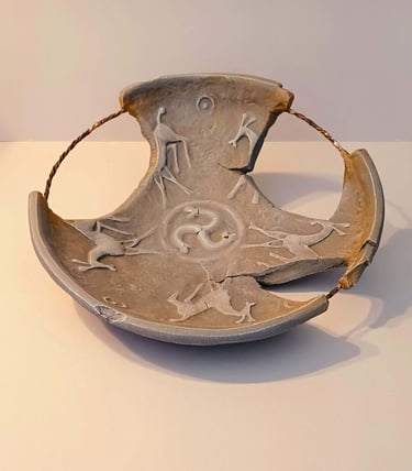 A fragmented bowl-like sculpture with embossed horse figures and symbols in rust/brown hues