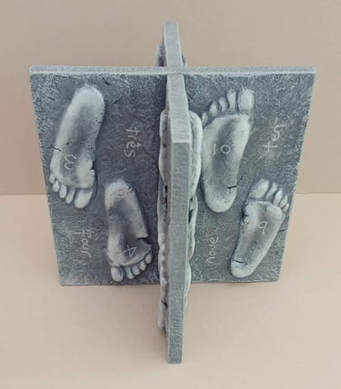 Two intersecting relief sculptures forming an X shape, and depicting three dimensional footprints.