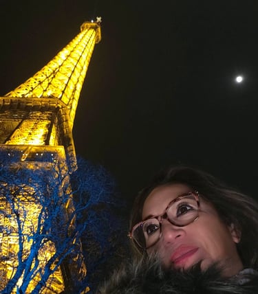 Mujer se toma una selfie frente a la Torre Eiffel iluminada por la noche en París. 