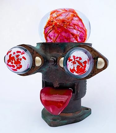 Assemblage robot head with red glass brain, bloodshot eyes and tongue sticking out.
