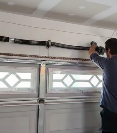 Professional technician performing a garage door spring repair on a residential overhead door.