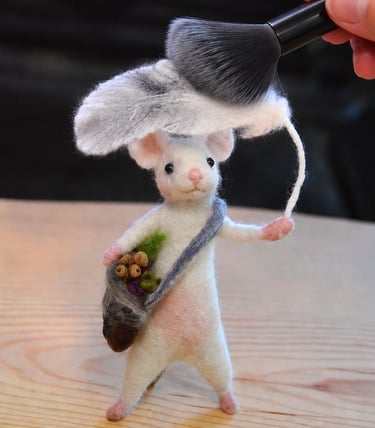 Figurine d'une petite souris en laine feutrée dépoussiérée avec une brosse douce