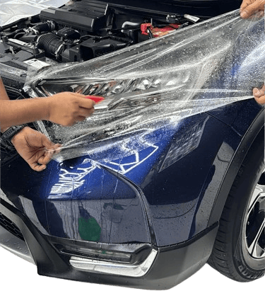 : Technician applying paint protection film to car headlight at One 7 Garage
