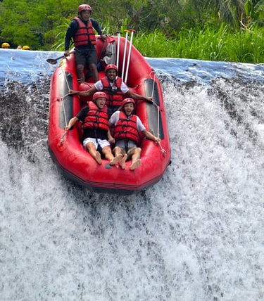 A group of people wearing life jackets and helmets enjoy a white water rafting adventure down a waterfall.