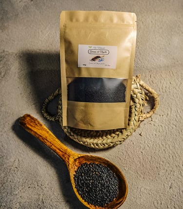 Black seed nigella sativa grains in a wooden spoon and kraft paper packaging pouch.