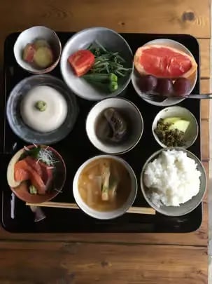 Traditional Japanese farm-to-table meal served on a black tray with multiple small dishes