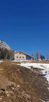  Traditional stone alpine rifugio in the Dolomites with snow patches and blue sky
