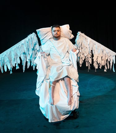 Jamie Hale sits in an electric wheelchair made up like a bed, hospital gown wings splayed out wide