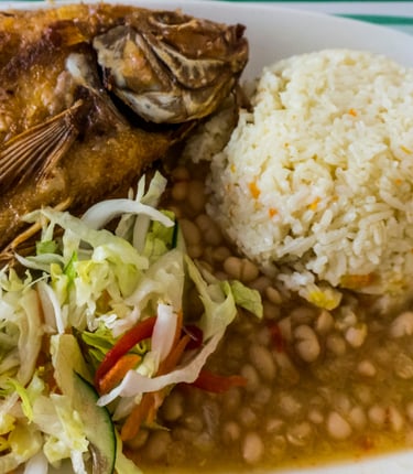 a plate of food with beans, white rice and fried fish