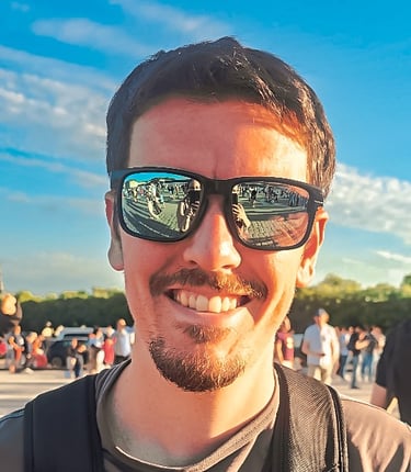 Portrait d’un homme souriant avec des lunettes de soleil reflétant une foule, ciel bleu et ambiance ensoleillée d’événement