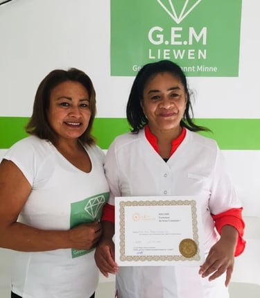 Deux femmes souriantes posant dans un centre de formation G.E.M. Liewen, l’une tenant un certificat
