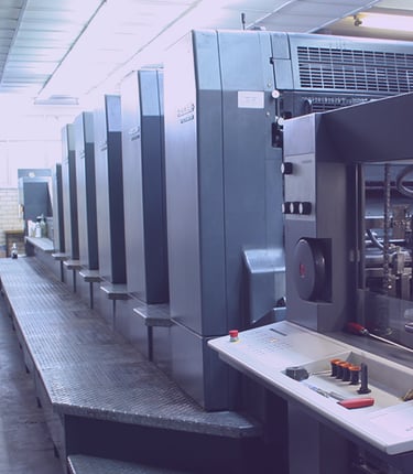 Impressora offset industrial em uma instalação comercial produzindo pilhas de papel de alto volume. 