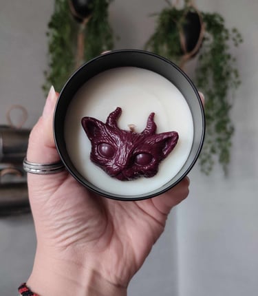 Bougies à la cire blanche, avec un fondant en forme de chat cornu, bordeaux. Contenant en métal noir