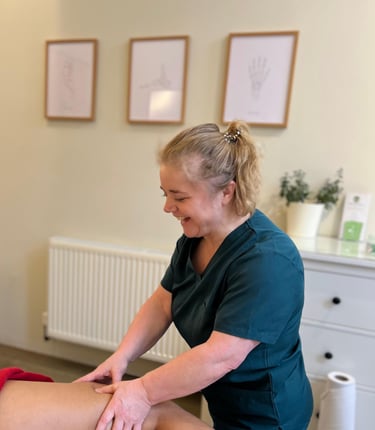 female massage therapist delivering sports massage to patient in clinic