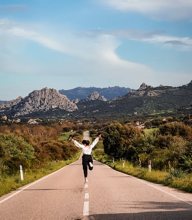 Girl jumping on Valle della Luna panoramic road near Aggius, Sardinia