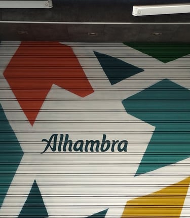 Graffiti corporativo Cervezas Alhambra en cierre metálico de restaurante MadreSelva en Sevilla