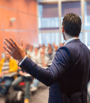 a man in a suit and tie is giving a presentation