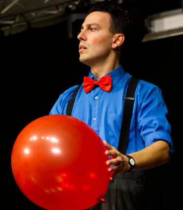 Pascal the clown in scena con un palloncino rosso fiammante come il suo papillon