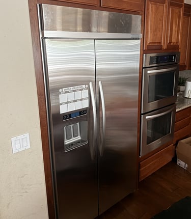 Built-in stainless steel French door refrigerator next to double wall ovens.