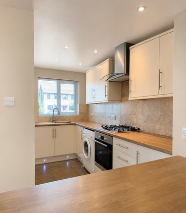 Modern L-shaped kitchen with cream cabinets, wood countertops, built-in oven, gas hob, Littlemore