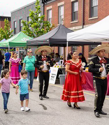 A lively crowd enjoying colorful tropical decorations and live Latin music at an outdoor festival in downtown London.