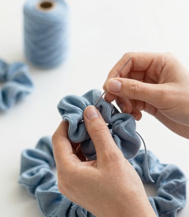 Close-up of hands sewing a luxurious scrunchie in a cozy workshop.