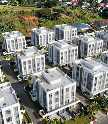 Drone perspective of a residential cluster nestled in green hills, bright daylight, Sentul.
