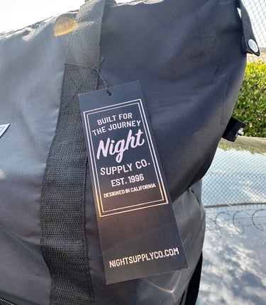 Black Night Supply Co. duffel bag with woven handle and branded hang tag