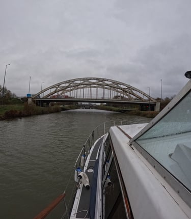 a boat traveling down a river with a bridge in the background