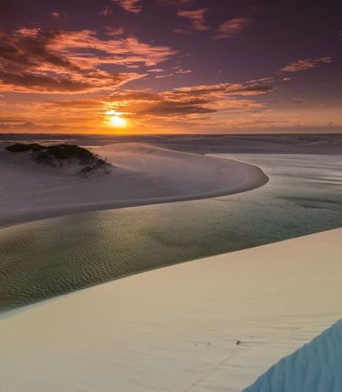 a sunset over a beach with a river running through it