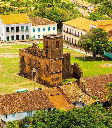 a church with a clock tower in the middle of a lush green field