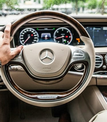 A person holding a steering wheel while driving, representing our professional car service.