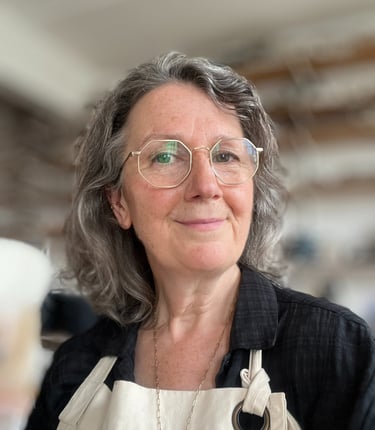 Ceramic artist Anna Butler looking to camera, in her North London ceramic studio