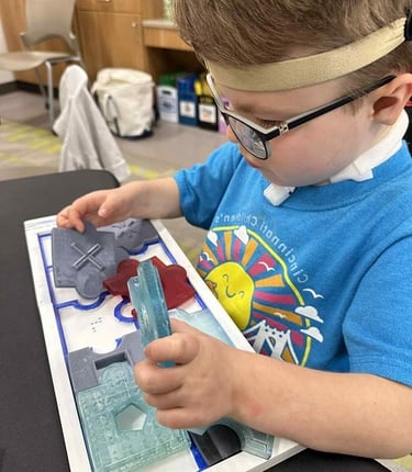 young visually impaired child focusing on a tactile puzzle