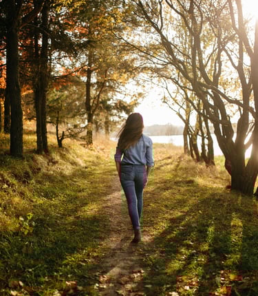 a woman walking down a path in the woods
