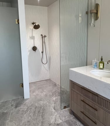 Modern master bathroom featuring a walk-in shower with textured tile and marble vanity.