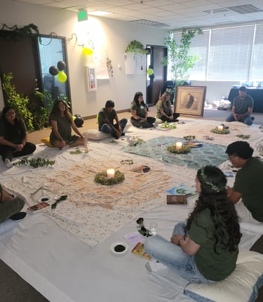 A group of people sitting in a circle on floor cushions for a spiritual healing ceremony with candles.