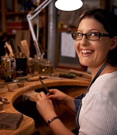 Mujer elaborando joyería con herramientas.